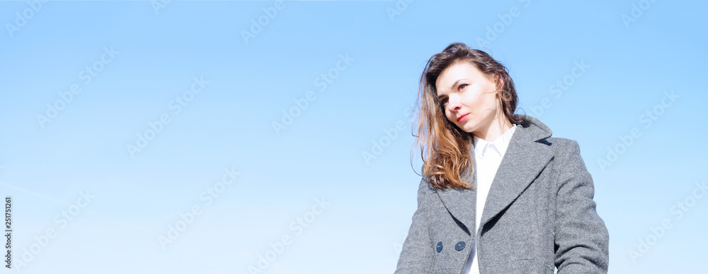 Fashion portrait of a girl in a coat against a blue sky. Fashion portrait of a girl in a coat against a blue sky.