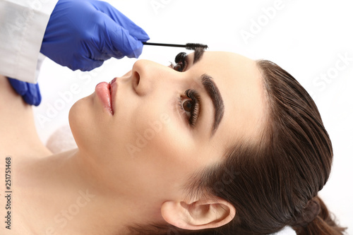 Young woman undergoing eyebrow correction procedure in beauty salon