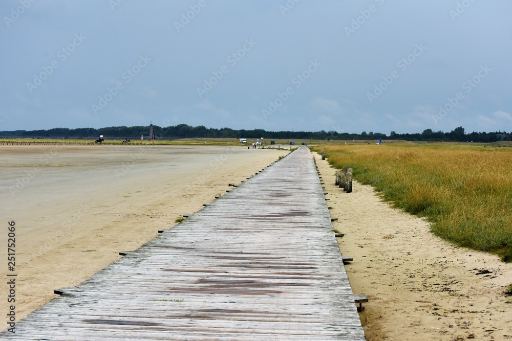 Wooden pier on the German North Sea coast on the sandy beach with dike