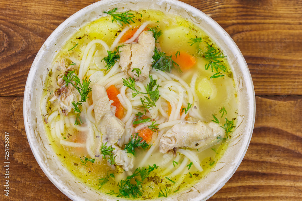 Chicken soup with noodles and vegetables on wooden table. Top view Chicken soup with noodles and vegetables on wooden table. Top view