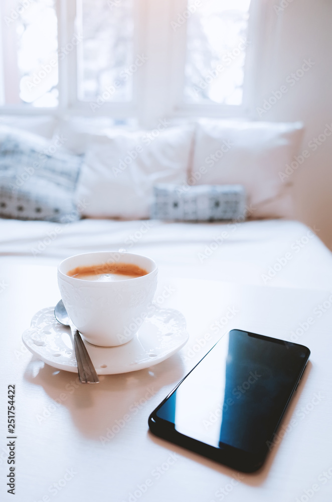 Mobile phone with coffee on a table in bed room Mobile phone with coffee on a table in bed room