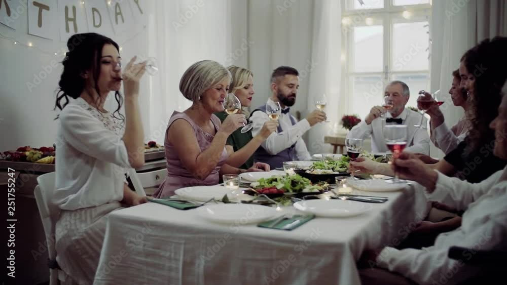 A big family sitting at a table on a indoor birthday party, drinking wine. A big family sitting at a table on a indoor birthday party, drinking wine.