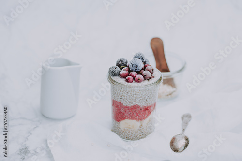 Homemade vegan chia pudding made of white chia seeds and almond milk with frozen berries on top. White background