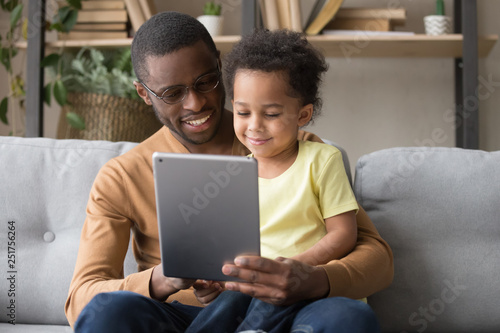 Happy african dad and little son using tablet at home