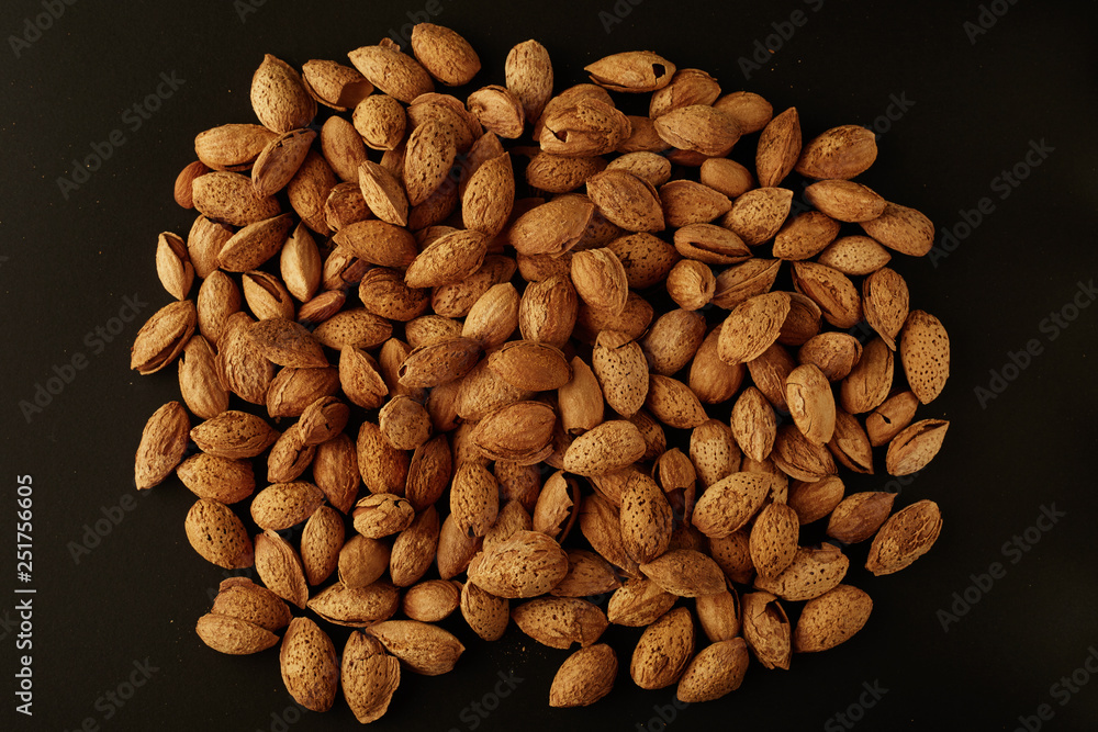 Top view of handful of pecans, almonds on a black background Top view of handful of pecans, almonds on a black background