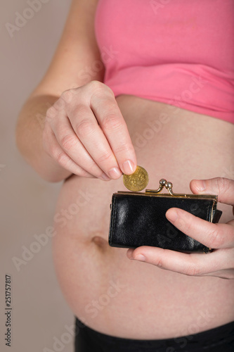 Young pregnant woman keeps small leather purse.