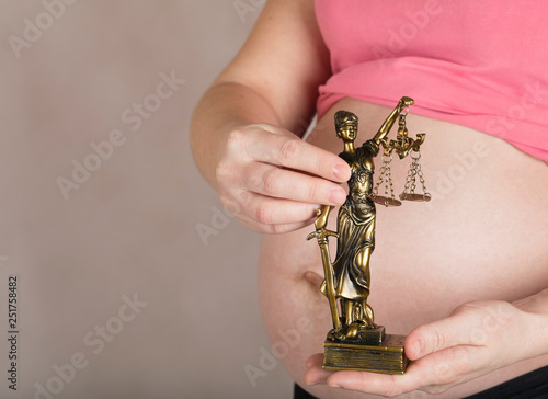 Young pregnant woman keeps statue of Themis.