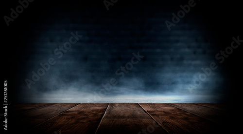 Dark empty room with brick walls and neon lights, smoke, rays. Brick wall, concrete and wooden table. © MiaStendal