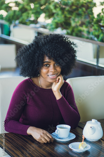 Happy smiling african-american girl at cafe table.