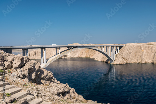 Deep blue water and rocky landscape with bridge which connects the Isle of Pag with the main land of Croatia