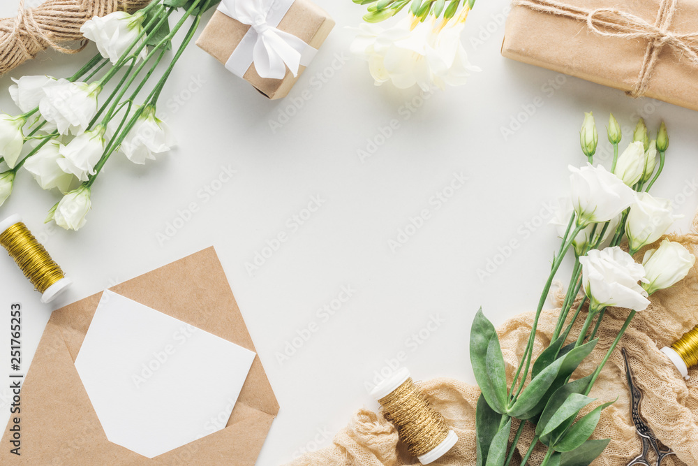 top view of flowers, wrapped gifts, envelope with empty card and cloth on grey background top view of flowers, wrapped gifts, envelope with empty card and cloth on grey background