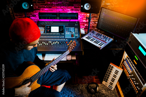 asian male musician recording acoustic guitar track in home studio photo