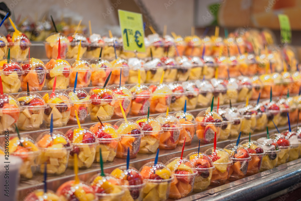 Rows of ready-to-eat fruit in plastic cups on the market. The concept of a healthy snack or quality, pricing or food delivery.