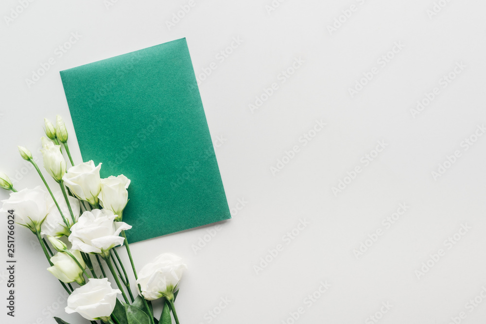 top view of empty green envelope with flowers on grey background top view of empty green envelope with flowers on grey background