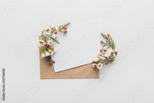 top view of empty blank with brown envelope and flowers on grey background © LIGHTFIELD STUDIOS