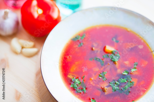 Borsch traditional Ukrainian and Russian soup with meat, beets and cabbage. Red soup in plate on the wooden background with spices and vegetables. Top view. Close up. 