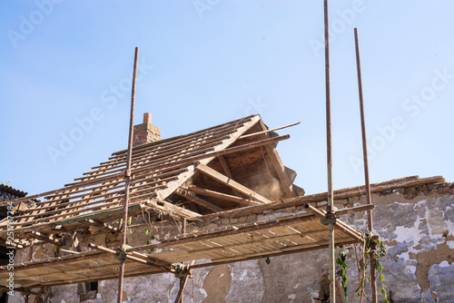 Litovel, Czech Republic August 3th 2018, scaffold standing by a clay house under reconstruction. Roof construction and timbers without tiles. Half of the roof blown away by the twind. photo