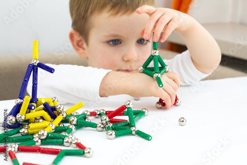 Cute little child boy playing magnets toy for brain development, fine motor skills and creativity concept photo