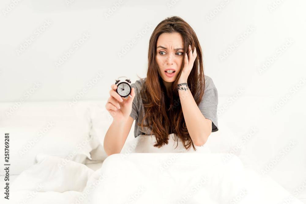 Beautiful young woman waking late for work in the morning with alarm clock. lifestyle concept Beautiful young woman waking late for work in the morning with alarm clock. lifestyle concept