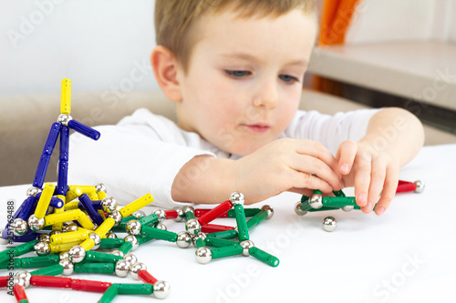 Cute little child boy playing magnets toy for brain development, fine motor skills and creativity concept photo