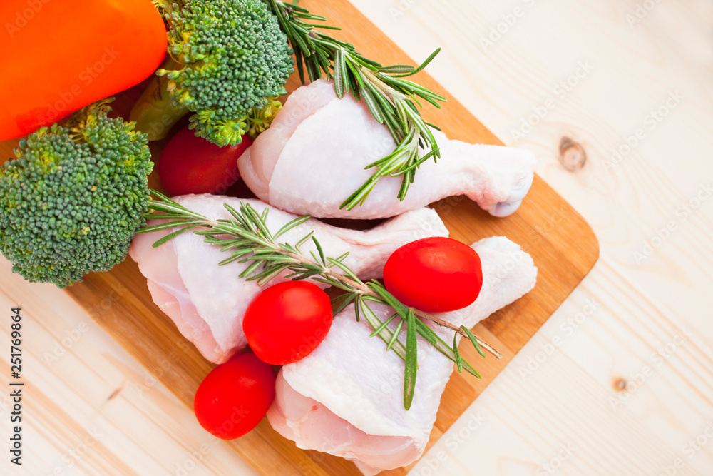Raw chicken legs with spices, vegetables and rosemary on the dark wooden cutting board. Recipes, healthy food, lifestyle concept. Top view. Close up.