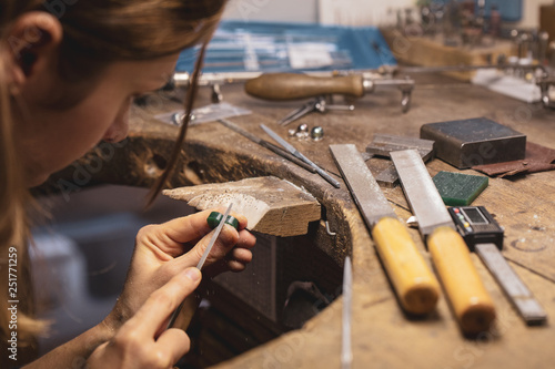 Craftwoman working on a jewel cast with a file