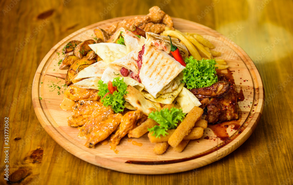 Pub menu snack. Tasty delicious snacks. Snack for beer. Restaurant food. Wooden board with lot french fries fish sticks burrito and meat steak served with salad. High calorie snack for group friends Pub menu snack. Tasty delicious snacks. Snack for beer. Restaurant food. Wooden board with lot french fries fish sticks burrito and meat steak served with salad. High calorie snack for group friends