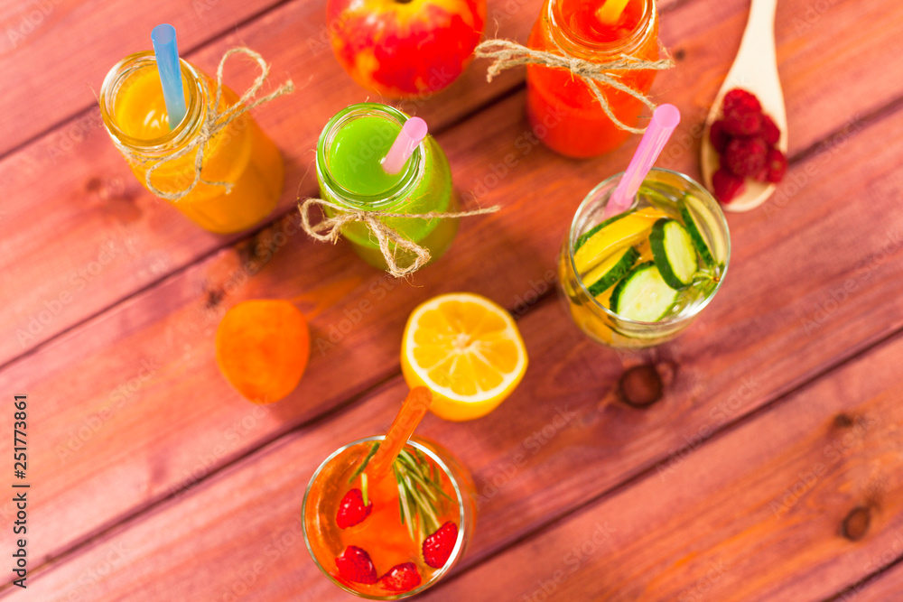 Fototapeta premium Fresh detox juices in glass bottles on the wooden background. Fruits and berries. Lifestyle, vegan food and drink, health care, diet and summer concept. Top view. Close up.