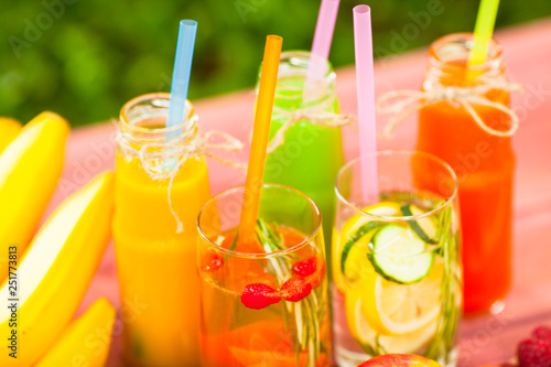 Fresh detox juices in glass bottles on the wooden background. Fruits and berries. Lifestyle, vegan food and drink, health care, diet and summer concept. Top view. Close up.