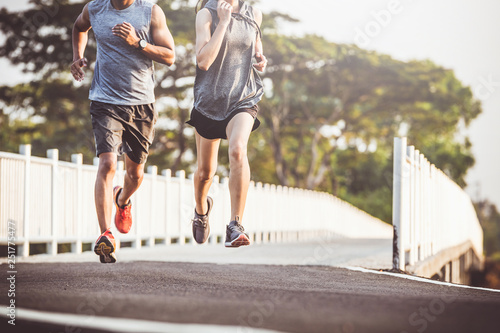 young couple runner running on running road in city park