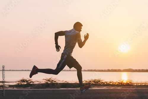 young man runner running on running road in city park