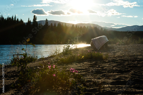Canoe turned over on shore of Nisutlin River in boreal forest taiga wilderness of Yukon Territory, Canada photo