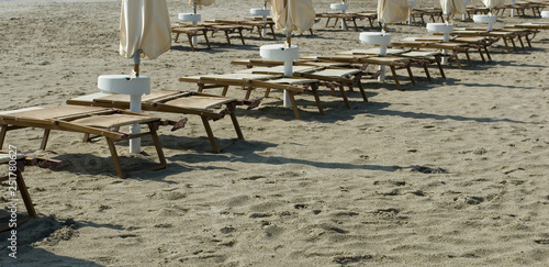 sandy beach with deckchairs and umbrellas of beige color, by the sea, sunny and windy day, summer, vacation, travel, mediterranean, Arma di Taggia, Liguria, Riviera, Italy photo