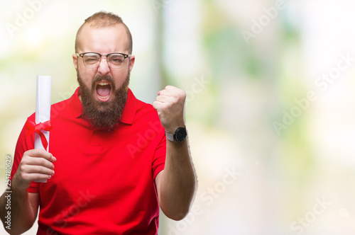 Young hipster man wearing glasses and holding degree over isolated background annoyed and frustrated shouting with anger, crazy and yelling with raised hand, anger concept