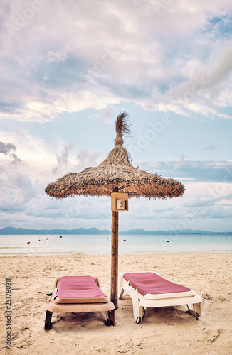 Umbrella and pair of sunbeds on a beach  color toned picture.