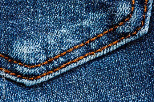 Fragment of a classic blue denim texture with orange stitching