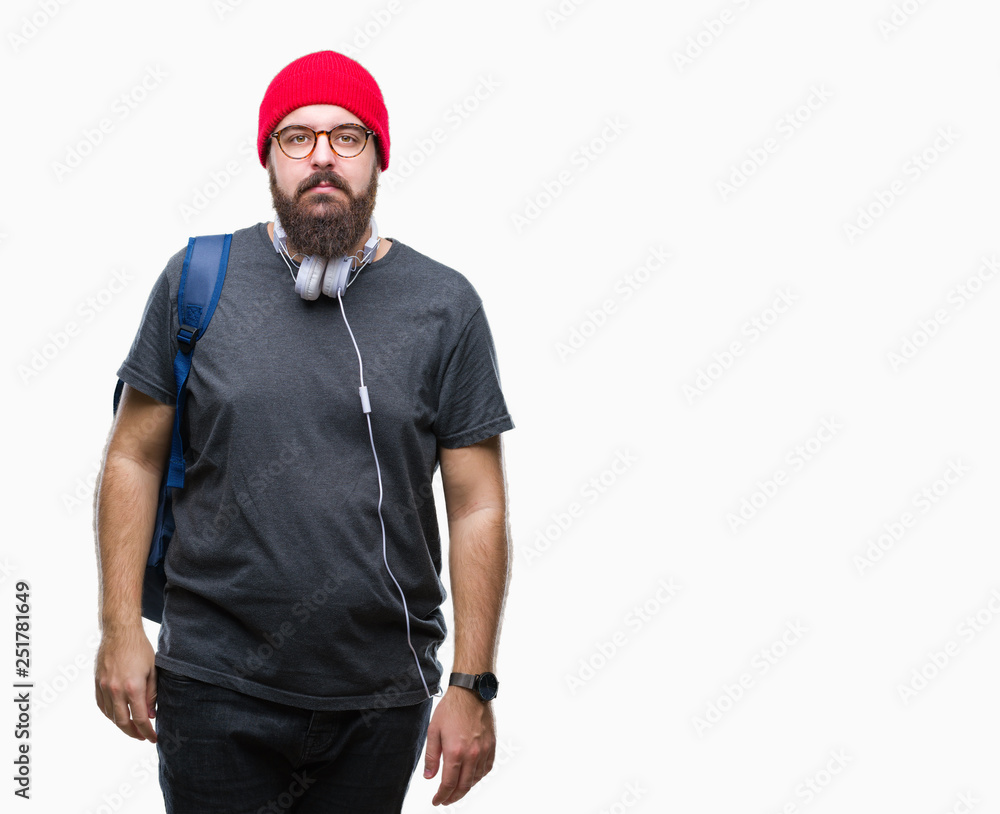 Young hipster man wearing red wool cap and backpack over isolated background with serious expression on face. Simple and natural looking at the camera.