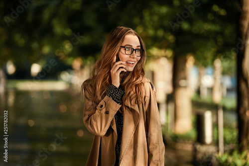 Portrait of beautiful woman using cell phone while walking through empty boulevard