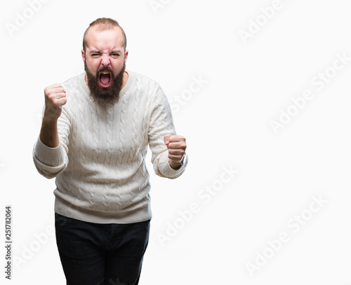 Young caucasian hipster man wearing winter sweater over isolated background angry and mad raising fist frustrated and furious while shouting with anger. Rage and aggressive concept.