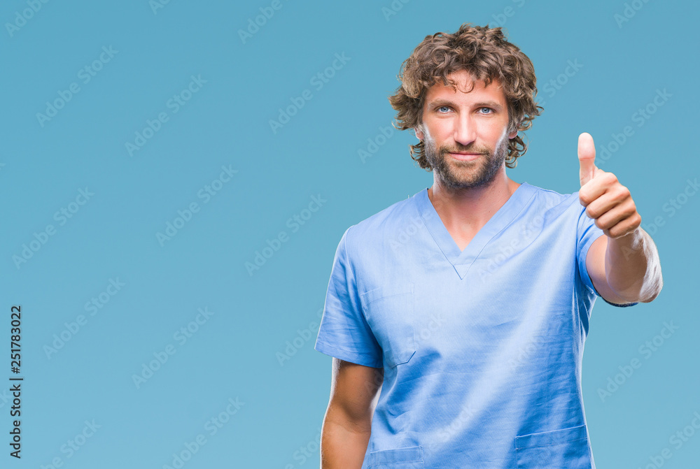 Handsome hispanic surgeon doctor man over isolated background doing happy thumbs up gesture with hand. Approving expression looking at the camera with showing success. Handsome hispanic surgeon doctor man over isolated background doing happy thumbs up gesture with hand. Approving expression looking at the camera with showing success.