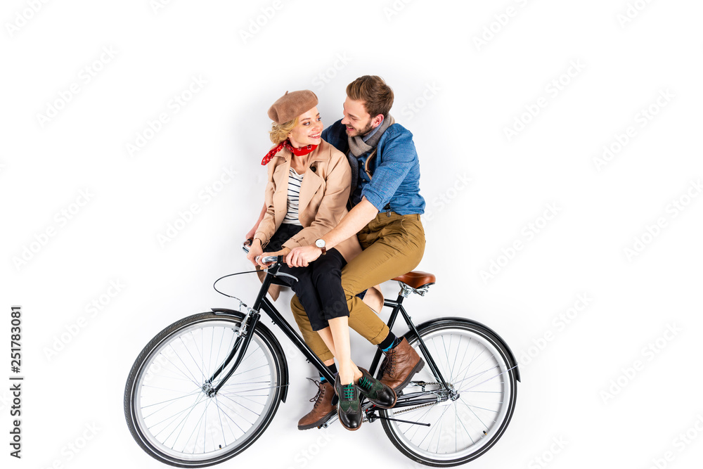 Happy couple sitting on bicycle and looking at each other on white background Happy couple sitting on bicycle and looking at each other on white background