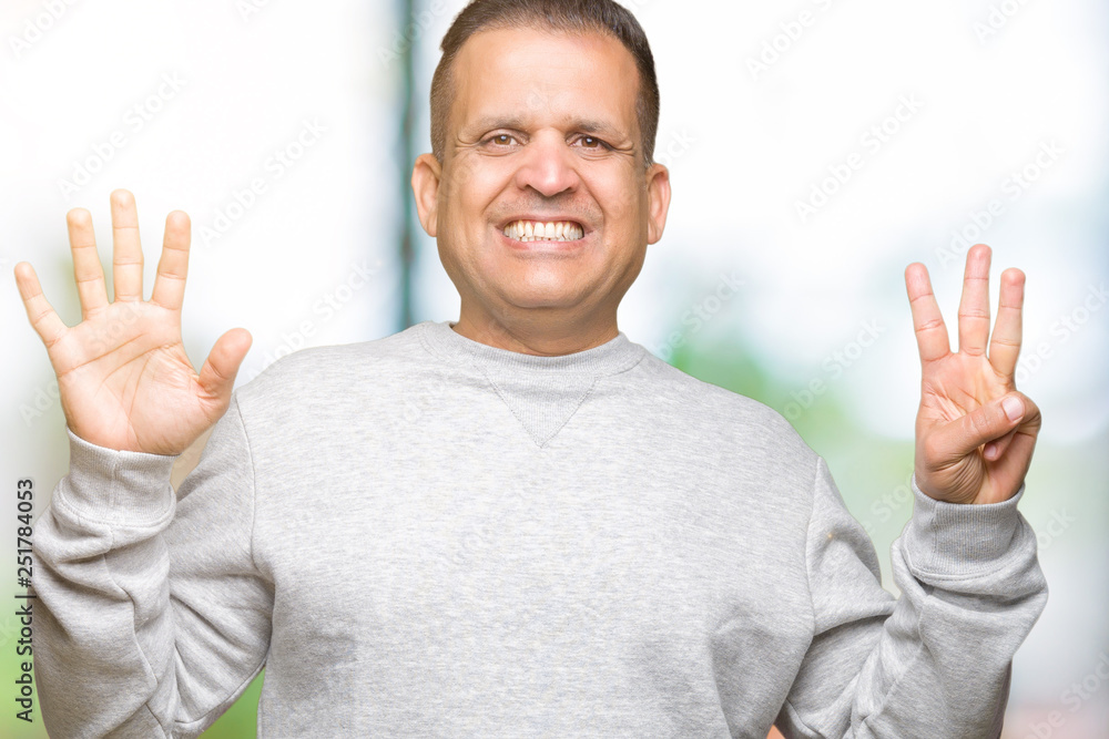 Middle age arab man wearing sport sweatshirt over isolated background showing and pointing up with fingers number eight while smiling confident and happy. Middle age arab man wearing sport sweatshirt over isolated background showing and pointing up with fingers number eight while smiling confident and happy.