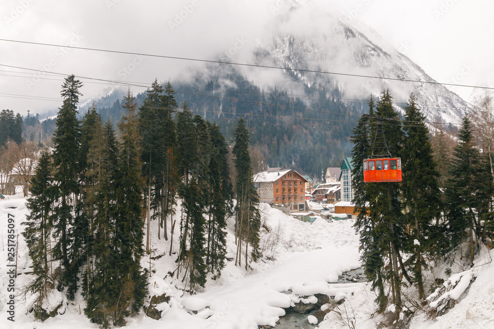 Red Ski lift in the background of the winter mountains. The red trailer of the old cable car moves to the mountain top of the ski resort. Retro gondola. Red Ski lift in the background of the winter mountains. The red trailer of the old cable car moves to the mountain top of the ski resort. Retro gondola.