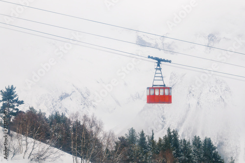 Red Ski lift in the background of the winter mountains. The red trailer of the old cable car moves to the mountain top of the ski resort. Retro gondola.
