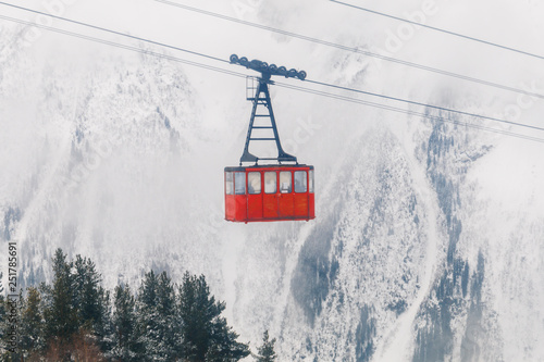 Red Ski lift in the background of the winter mountains. The red trailer of the old cable car moves to the mountain top of the ski resort. Retro gondola.