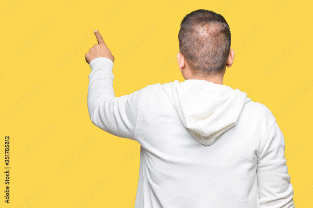 Middle age arab man wearing sweatshirt over isolated background Posing backwards pointing behind with finger hand Middle age arab man wearing sweatshirt over isolated background Posing backwards pointing behind with finger hand