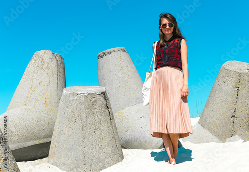 Young beautiful white caucasian woman with sunglasses on breakwater tier in Smiltyne - area of Klaipeda city near the port. On a sunny day in summer with azure blue sky. photo