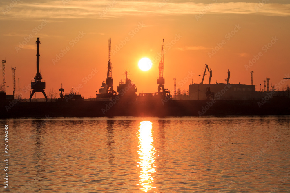 silhouettes of tower cranes in the sunset