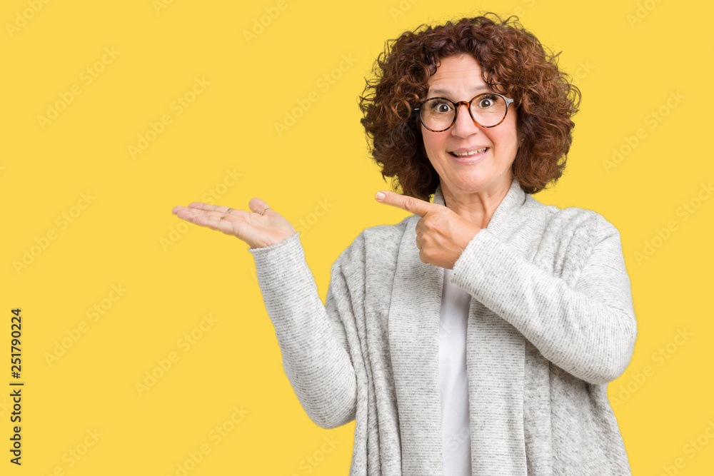 Φωτογραφία Beautiful middle ager senior woman wearing jacket and glasses over isolated background amazed and smiling to the camera while presenting with hand and pointing with finger