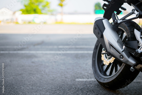 closeup tire and exhaust pipe of sport motorcycle with soft-focus and over light in the background